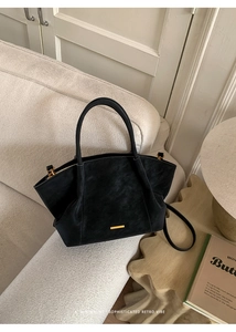 Detail view of retro black tote bag with gold hardware on a minimalist sofa