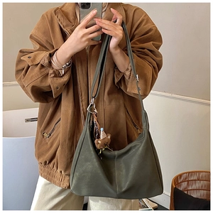 Dettaglio borsa hobo in pelle verde scuro con ciondolo a orsetto e tracolla larga