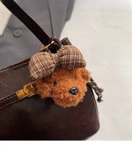Dettaglio di un ciondolo a forma di barboncino in peluche con fiocco su borsa a secchiello