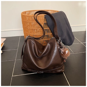 Detailed view of the brown leather hobo bag with zip closure and plush leopard bow charm