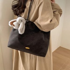 Detail of dark grey faux suede tote bag featuring a cute bunny pendant and golden metal charm