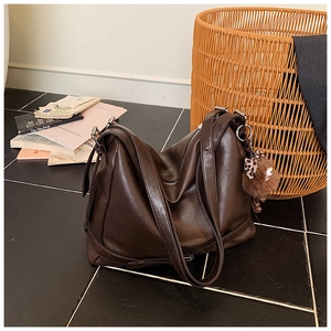 Detail of coffee brown tote bag featuring a plush bear charm and leopard bow accent