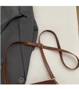 Détail de la bandoulière réglable en cuir marron avec boucle dorée sur sac matelassé