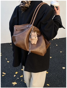 Dettaglio di una grande borsa tote in pelle marrone vintage con un tenero ciondolo a cane