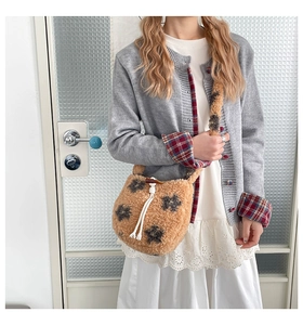 Detail of plush yellow bucket bag with floral patterns and a horn button closure