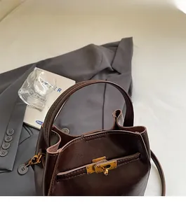 Dettaglio della borsa a secchiello in pelle marrone scuro con chiusura girevole dorata