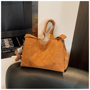 Close-up of brown quilted tote bag with a plush bear charm on a minimalist background