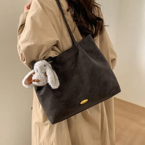 Detail of dark grey matte tote bag with golden buckle and white bunny charm accessory