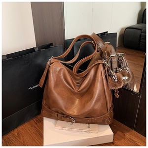 Detailed close-up of brown faux leather tote bag with owl plush and buckle accents