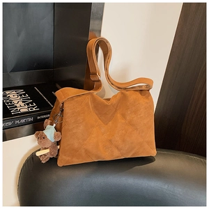 Detail of vintage brown quilted tote bag with a small plush bear charm and wide strap