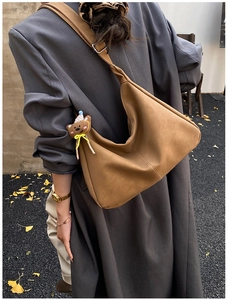 Borsa a mezzaluna marrone mostrata in una scena autunnale con foglie di ginkgo