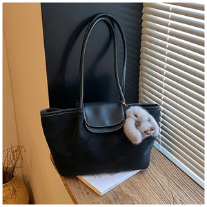 Detail of black suede tote bag with contrast stitching and plush rabbit charm