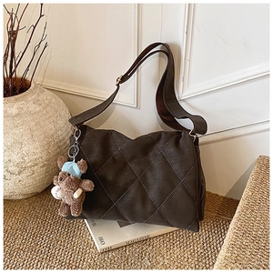 Detail of vintage quilted brown hobo bag with suede texture and cute bear charm