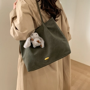 Detail of olive green tote bag with matte texture, gold hardware and plush rabbit charm
