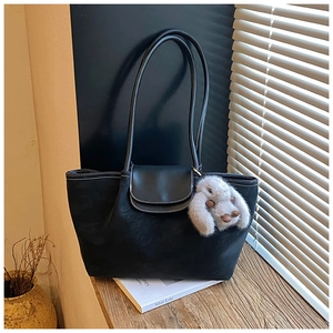 Close-up of black tote bag with white contrast stitching and cute rabbit pendant