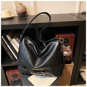 Close-up of black PU leather tote bag with unique bottom buckle and cute monster charm