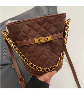 Détail d'un sac seau marron en daim matelassé avec chaîne dorée et fermoir pivotant