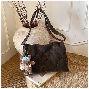 Detail of quilted leather tote bag with a cute teddy bear charm on a vintage background