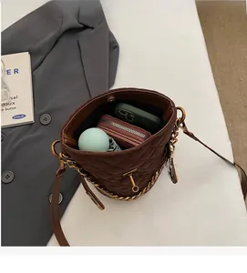 Vue intérieure montrant la grande capacité du sac seau en daim matelassé marron pour accessoires