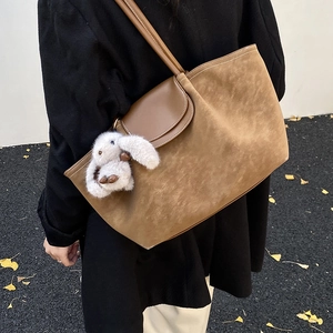 Minimalist brown suede tote bag with leather flap and plush bunny charm on shoulder strap
