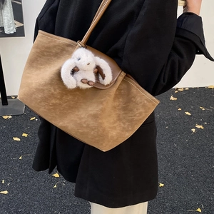 Brown faux suede tote bag featuring a cute white bunny plush pendant on a model in autumn