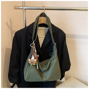 Dettaglio della borsa hobo in pelle verde vintage con tracolla larga e ciondolo a orso