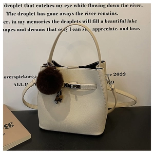 Detail van gebroken witte emmer tas van generfd leer met zilveren slot en pluche hanger