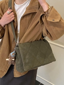 Olive green quilted crossbody bag with brown bear charm shown on model in a studio setting