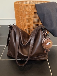 Large dark brown soft leather tote bag in hobo style with cute furry monster charm