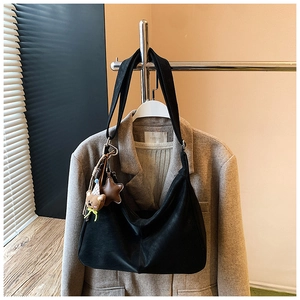 Dettaglio di una borsa tote nera opaca con ciondoli a forma di orso e stella
