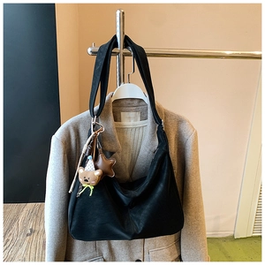 Dettaglio di una borsa tote nera grande con ciondoli a forma di orso e stella su appendino