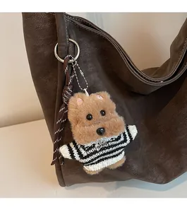 Close-up of a plush Yorkshire puppy charm with a TOP DOG tag on a dark leather bag