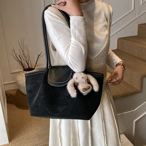 Detail of black tote bag with white stitching and cute long-eared rabbit charm