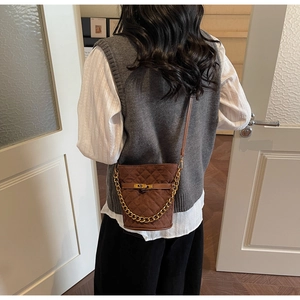 Detail of brown quilted bucket bag with gold chain strap and metallic turn-lock closure