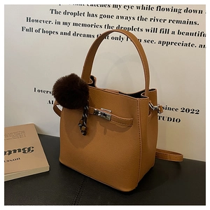 Detail van bruine bucket bag met lychee patroon, zilveren slot en pluche hanger