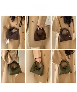 Detail of bow-knot suede tote bag in brown and olive green worn with beige coat