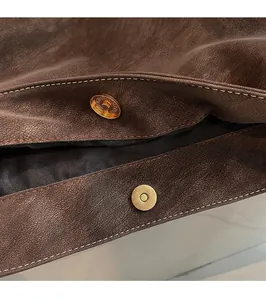 Detail of vintage brown PU leather tote showing gold magnetic clasp and stitching