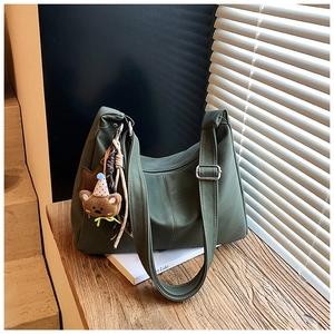 Dettaglio della borsa hobo in pelle verde scuro con ciondolo a forma di orso