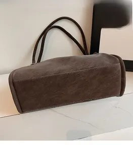 Detailed view of dark tote bag bottom with contrast stitching on faux leather material