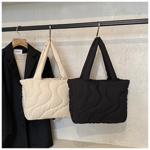 Quilted tote bags with wave pattern stitching in black and beige displayed on a hanger