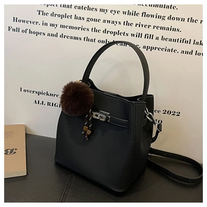 Detail van zwarte lederen emmer tas met zilveren draaisluiting en pluche pompon