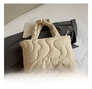 Close-up of beige quilted tote bag with wavy stitching and padded texture detail
