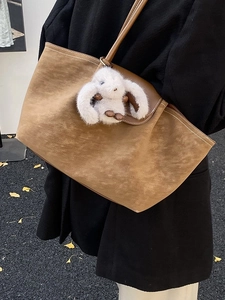 Brown suede tote bag with white bunny charm shown in a cozy outdoor autumn setting