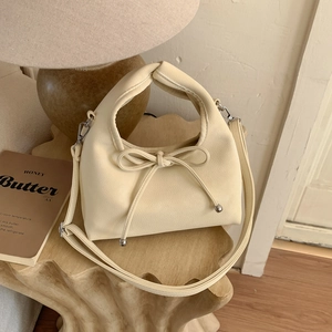 Detail of off-white leather handbag showing bow tie design and silver metal beads