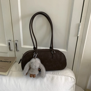Detailed view of dark brown suede shoulder bag with cute long-eared rabbit pendant