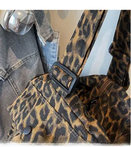 Detail of adjustable black plastic buckle and camouflage strap on canvas shoulder bag