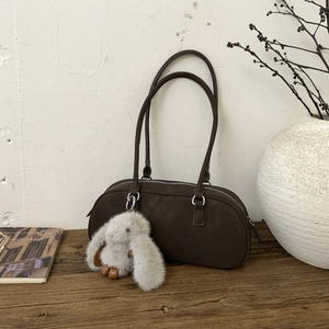 Detail of dark brown suede shoulder bag with a cute long-eared rabbit plush pendant