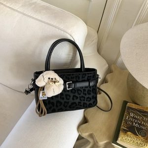 Dettaglio borsa in pelle nera con inserto leopardato e ciondolo a forma di cane di peluche