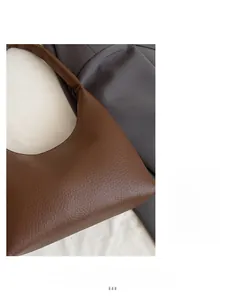 Detailed texture of brown pebble leather on a minimalist crescent-shaped shoulder bag
