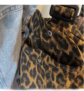 Detailed close-up of leopard print crossbody bag with metal snap pocket and canvas texture